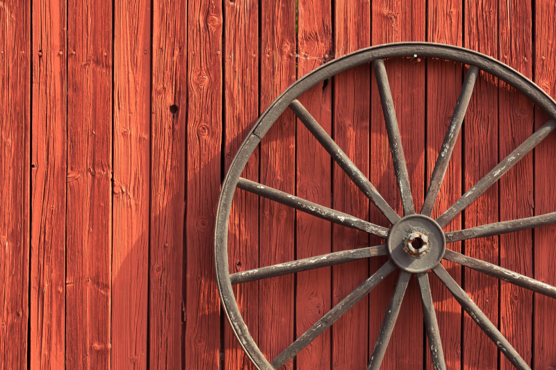 Wagon wheel leaning on barn